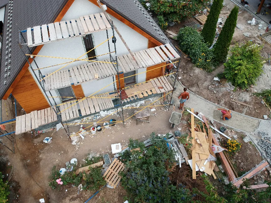Vue aérienne d'un chantier de ravalement de façade d'une maison individuelle montrant l'adaptation de l'échafaudage aux contraintes du terrain