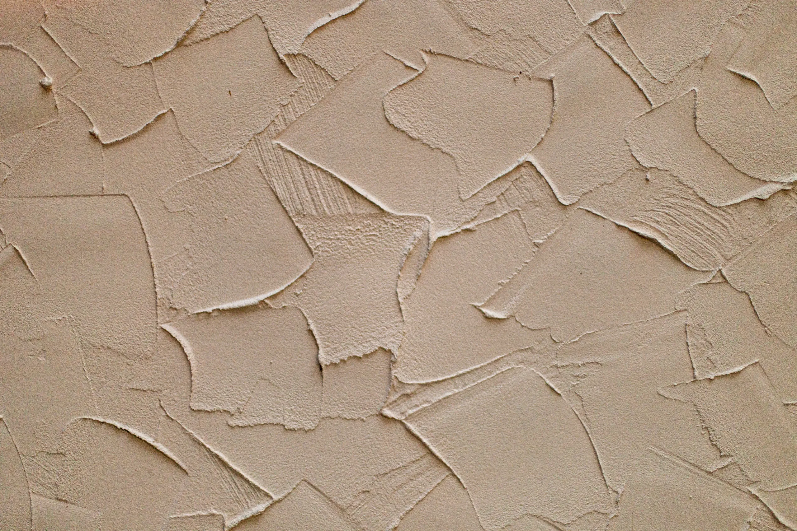 Gros plan sur un enduit de façade taloché de couleur gris clair avec un grain fin, lisse et régulier.