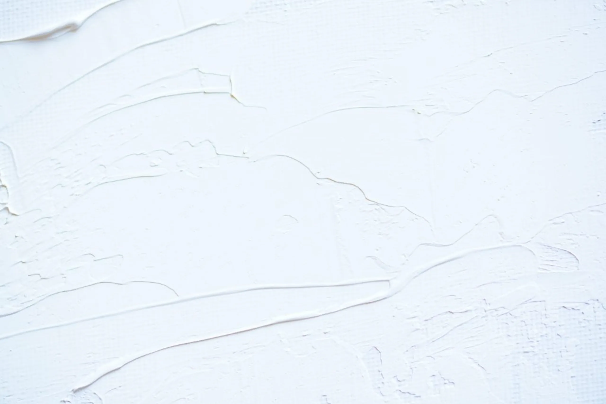 Gros plan sur un enduit de façade lissé blanc avec des effets de matière, des traces de taloche et de lame texturées.