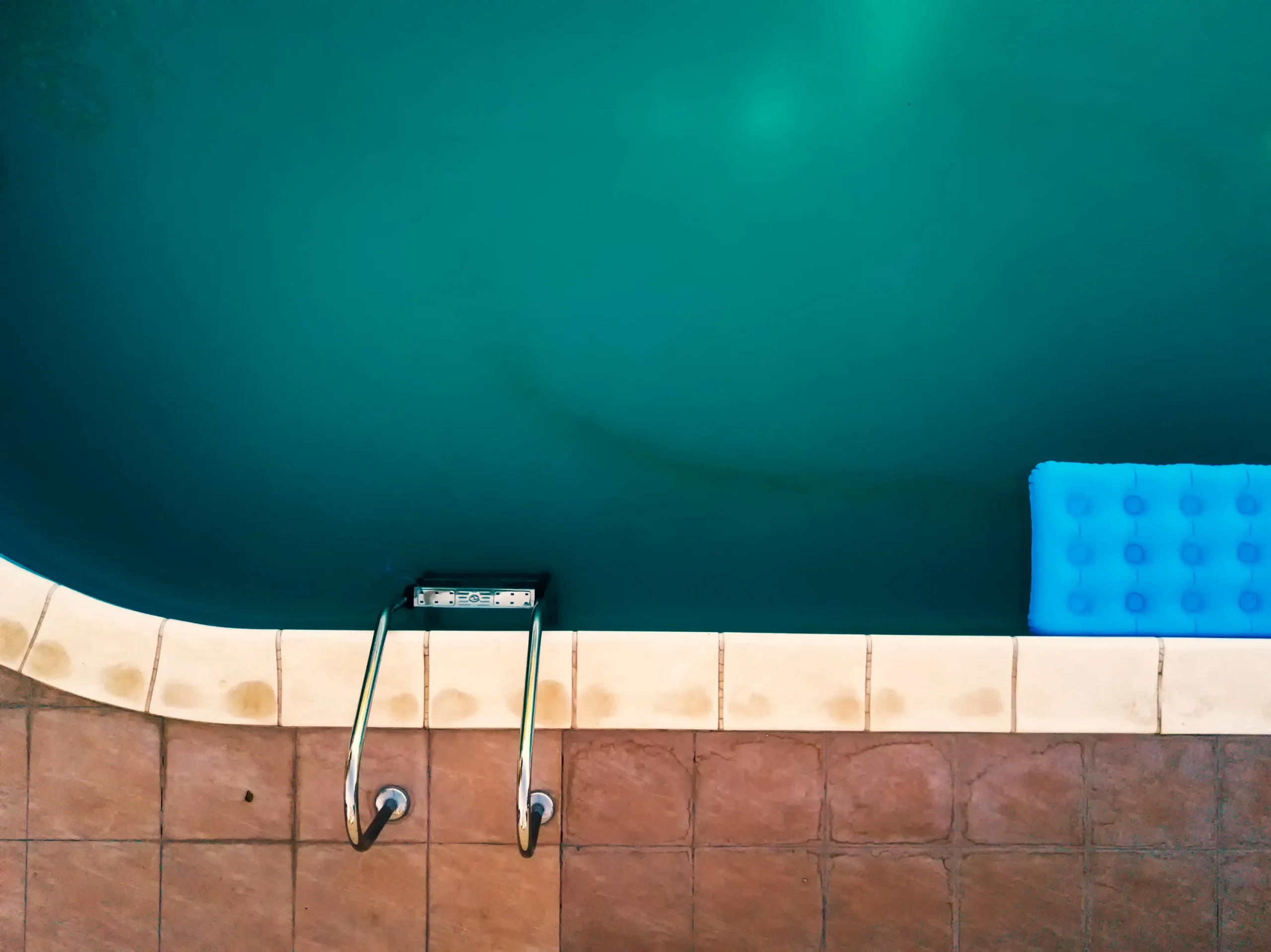Fin de chantier et nettoyage de piscine : vue du dessus d'un bassin d'eau propre avec plages de piscine dallées et finitions décoratives.